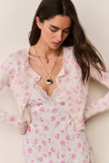 Woman wearing a pink floral cardigan and matching dress against a beige background
