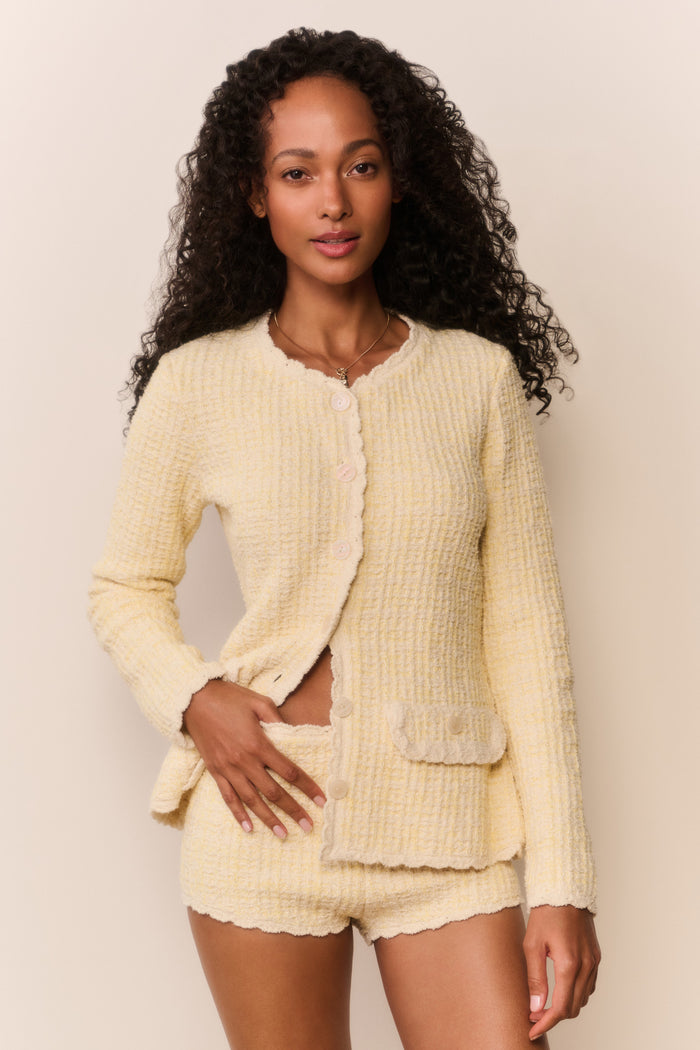 Woman wearing a light yellow jacket and matching shorts outfit against a plain background