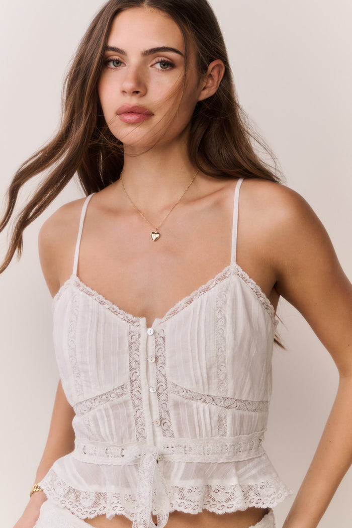 Woman wearing a white lace top against a plain background