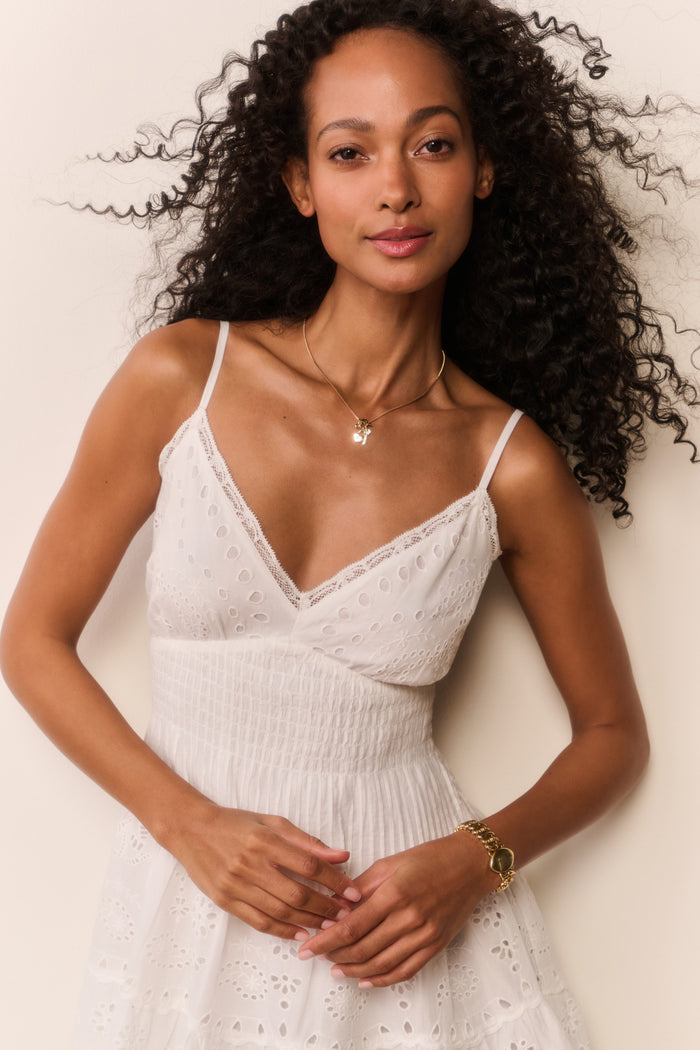 Woman wearing a white lace dress against a plain background