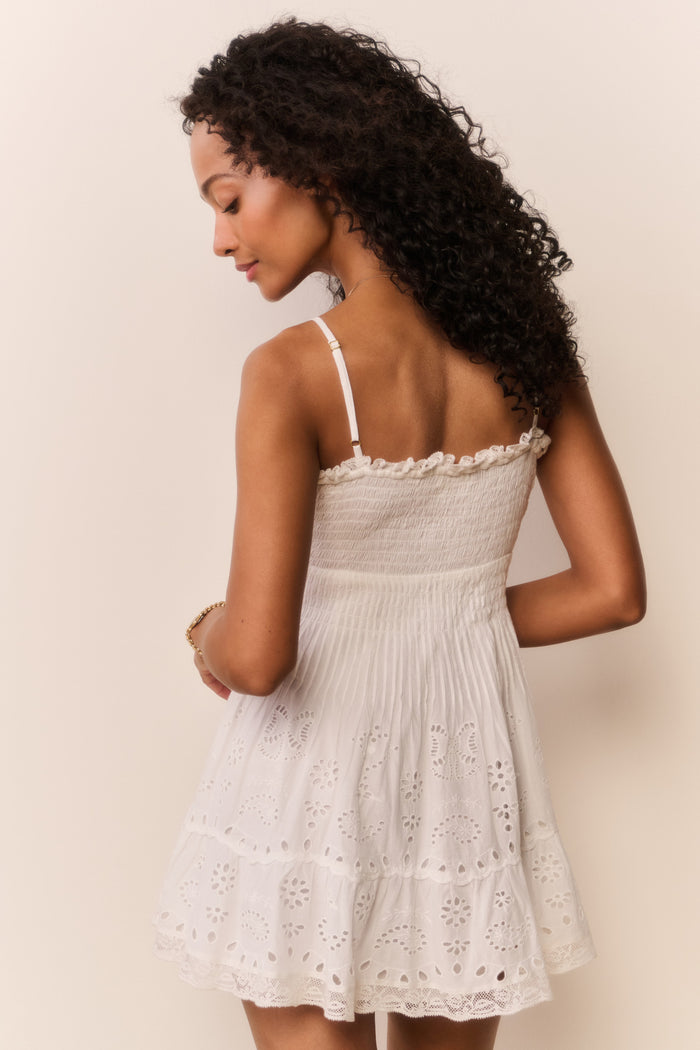 Woman wearing a white lace dress against a plain background