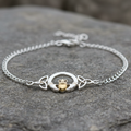 Silver bracelet with claddagh design on a stone surface