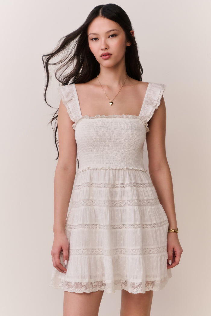 Woman wearing a white ruffle dress against a plain background