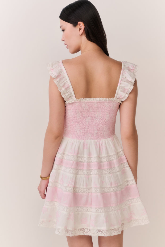 Woman wearing pink dress with lace details on a plain background