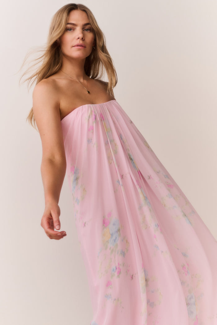 Woman wearing a pink strapless dress with floral patterns on a plain background