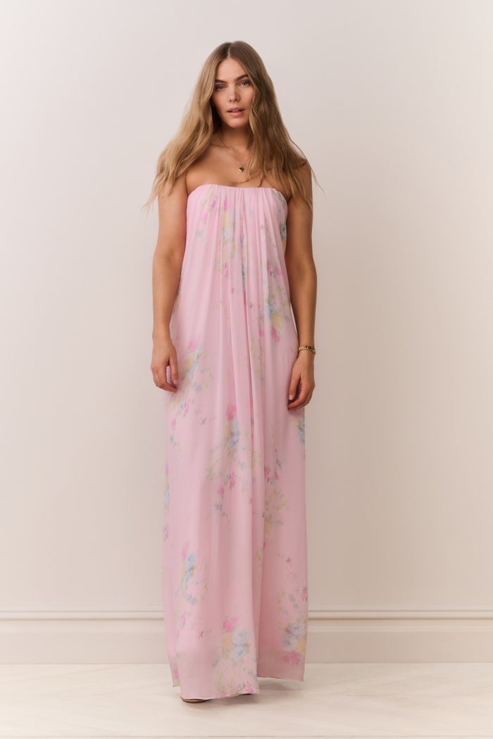 Woman wearing a pink strapless dress with floral patterns on a plain background