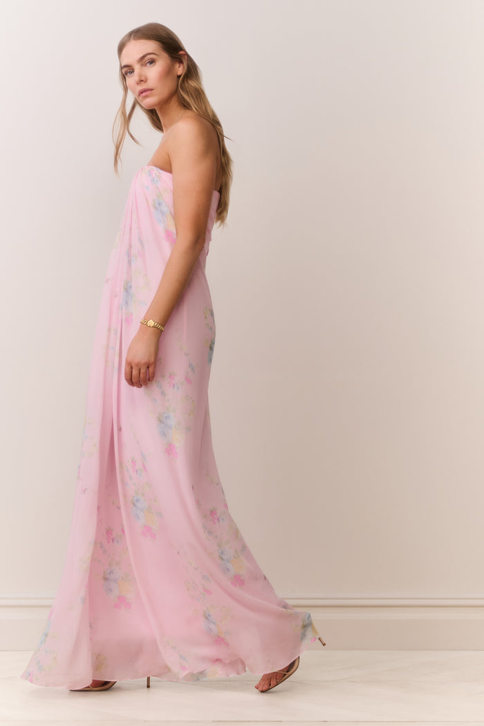 Woman wearing a pink strapless dress with floral patterns on a plain background