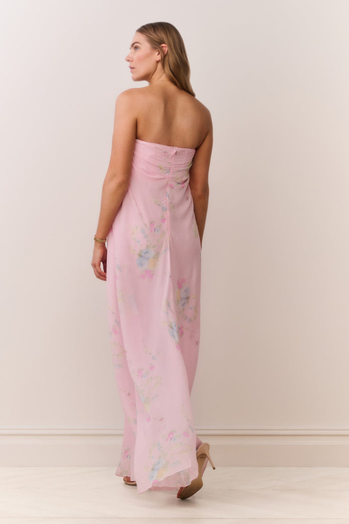 Woman wearing a pink strapless dress with floral patterns on a plain background