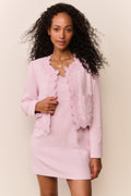 Woman wearing a pink dress with a matching evening jacket against a plain background
