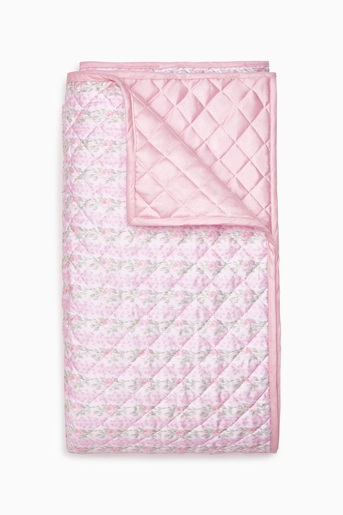 Pink quilt with floral pattern on a white background