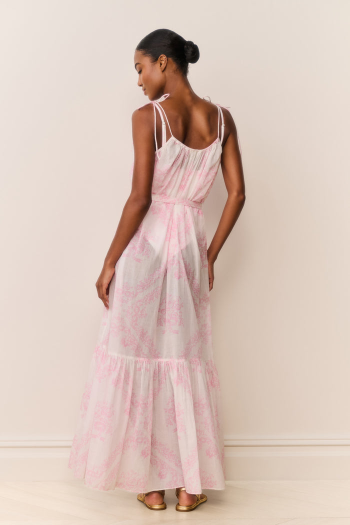 Woman wearing a pink and white patterned dress against a plain background