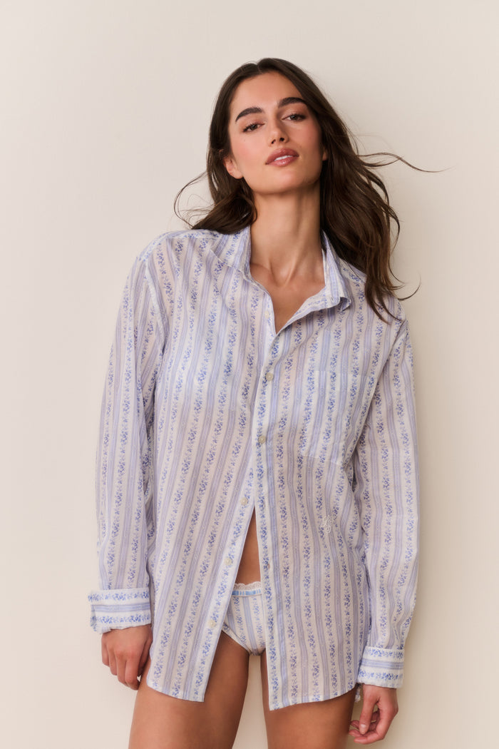 Woman wearing a floral striped button down shirt against a plain background