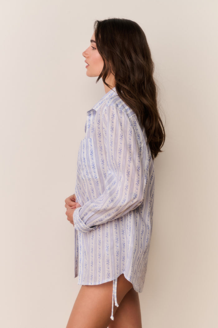 Woman wearing a floral striped button down shirt against a plain background