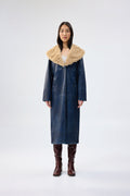 Navy faux leather coat with oversized tan faux fur collar, full-length relaxed fit, worn over brown knee-high boots, front view