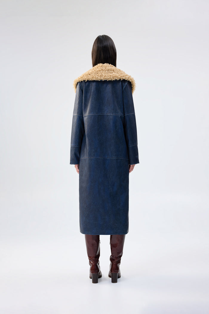Navy faux leather coat with oversized tan faux fur collar, full-length relaxed fit, worn over brown knee-high boots, back view