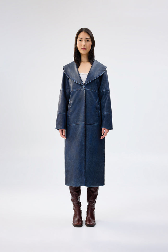 Navy faux leather coat with oversized shawl collar, full-length relaxed fit, worn over brown knee-high boots