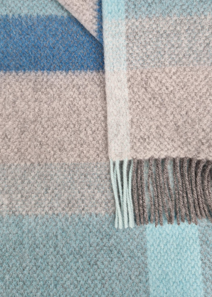 Close-up of a plaid fabric with blue, pink, and gray colors.