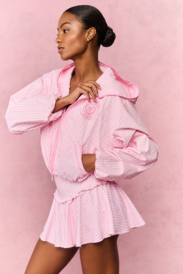 Woman wearing a pink outfit with a matching jacket against a pink background