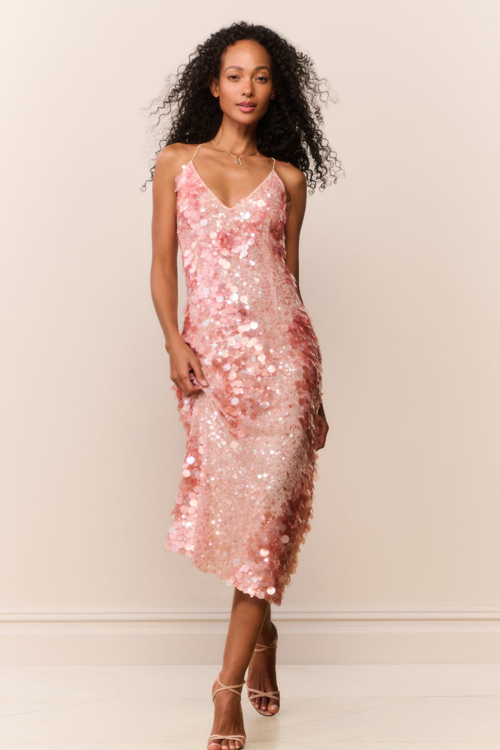 Woman wearing a peach sequin sleeveless midi dress on a white background