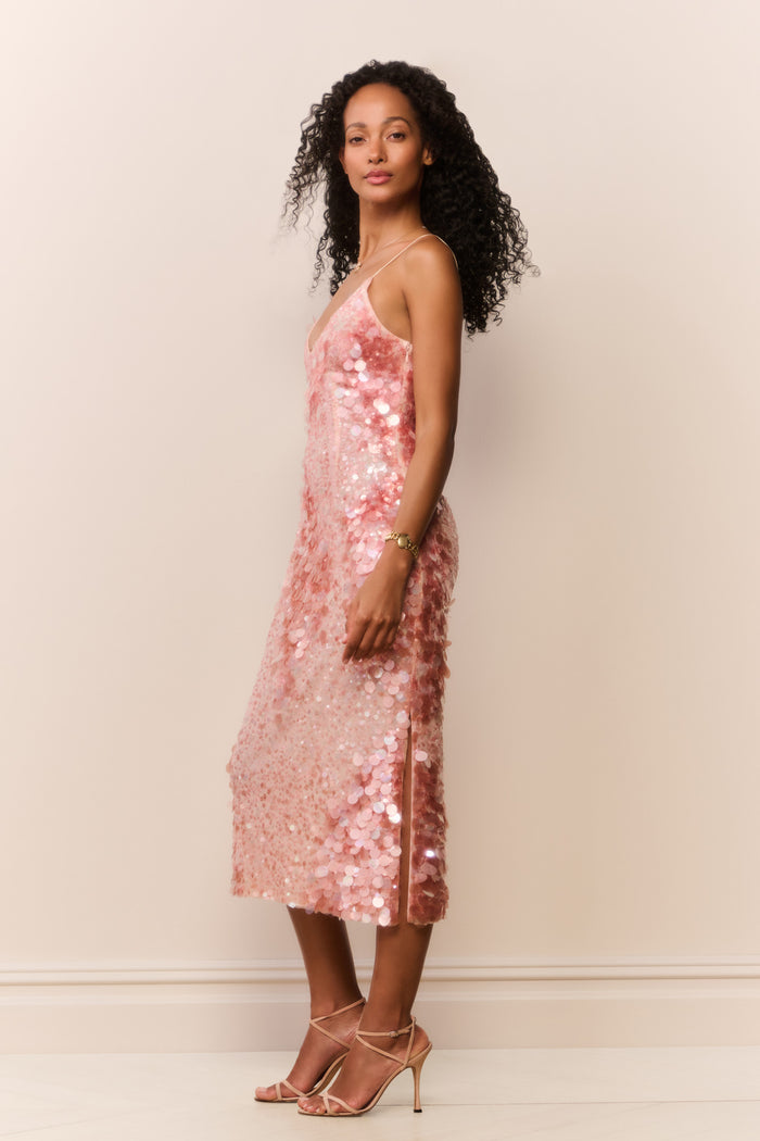 Woman wearing a peach sequin sleeveless midi dress on a white background