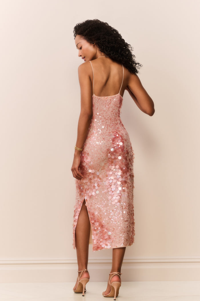 Woman wearing a peach sequin sleeveless midi dress on a white background