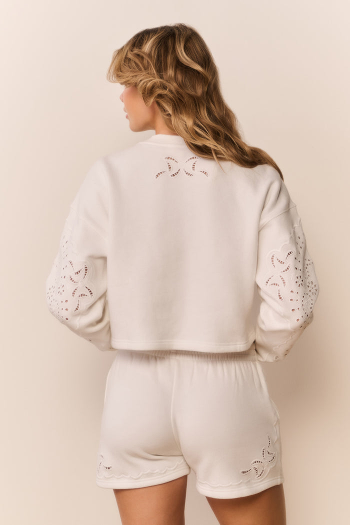 White eyelet accented pullover against a white background