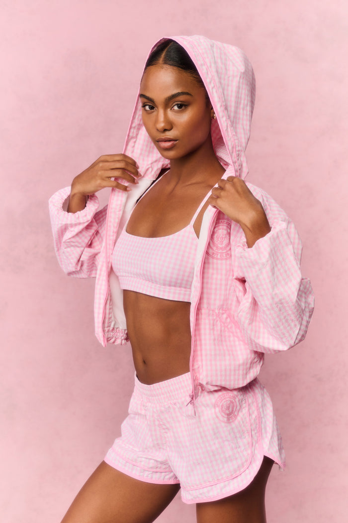 Person wearing a pink workout hoodie and shorts on a pink background