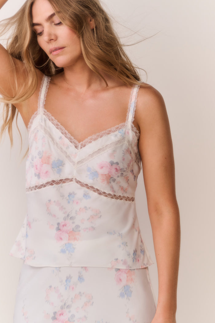 Woman wearing a floral lace satin camisole against a plain background
