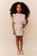 Young girl wearing a floral dress with ruffles from on a plain background