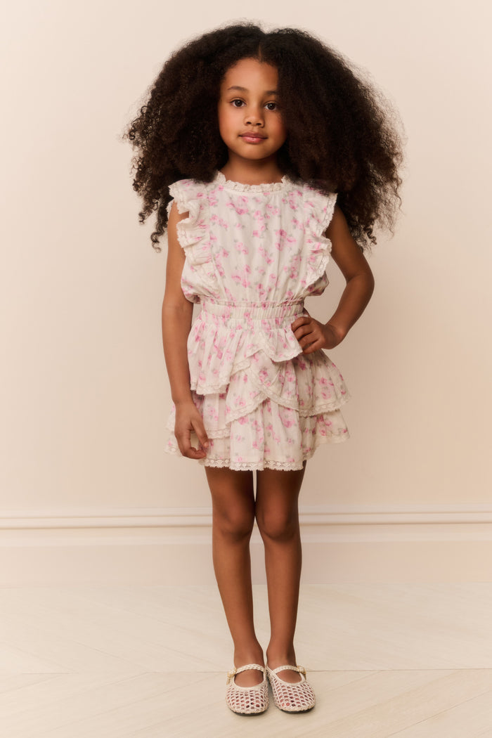Young girl wearing a floral dress with ruffles from on a plain background
