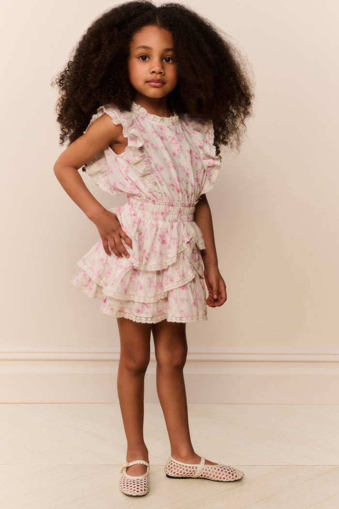 Young girl wearing a floral dress against a plain background