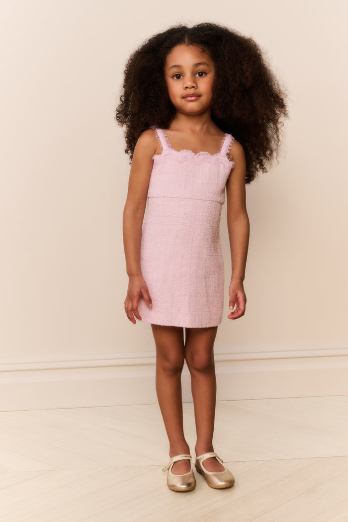 Young girl wearing a pink dress against a plain background