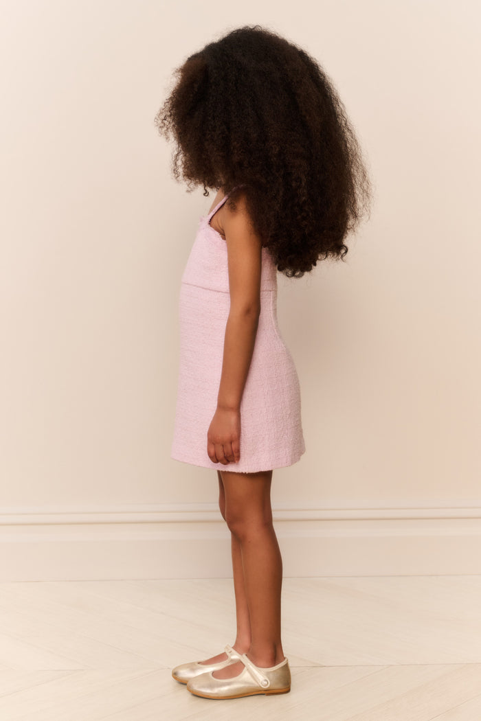 Young girl wearing a pink dress against a plain background