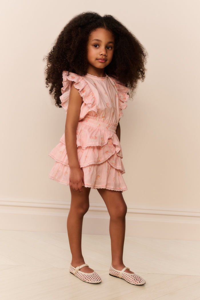 Child wearing a pink ruffled dress against a plain background