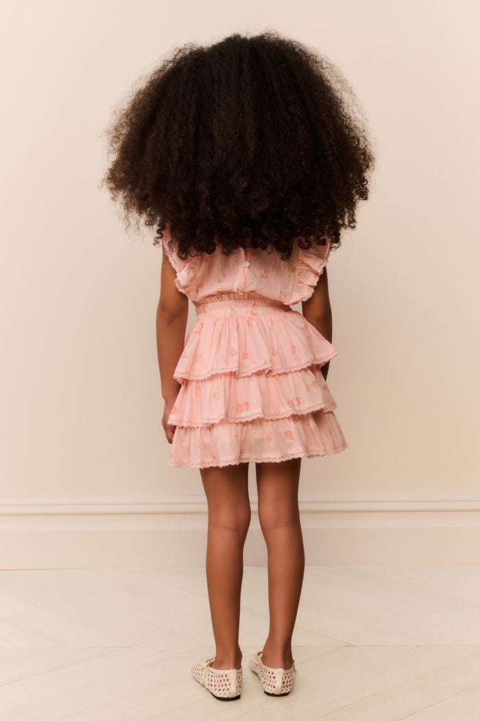 Child wearing a pink ruffled dress against a plain background