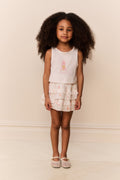 Young girl wearing ruffle white skirt with pink flowers and white sleeveless top