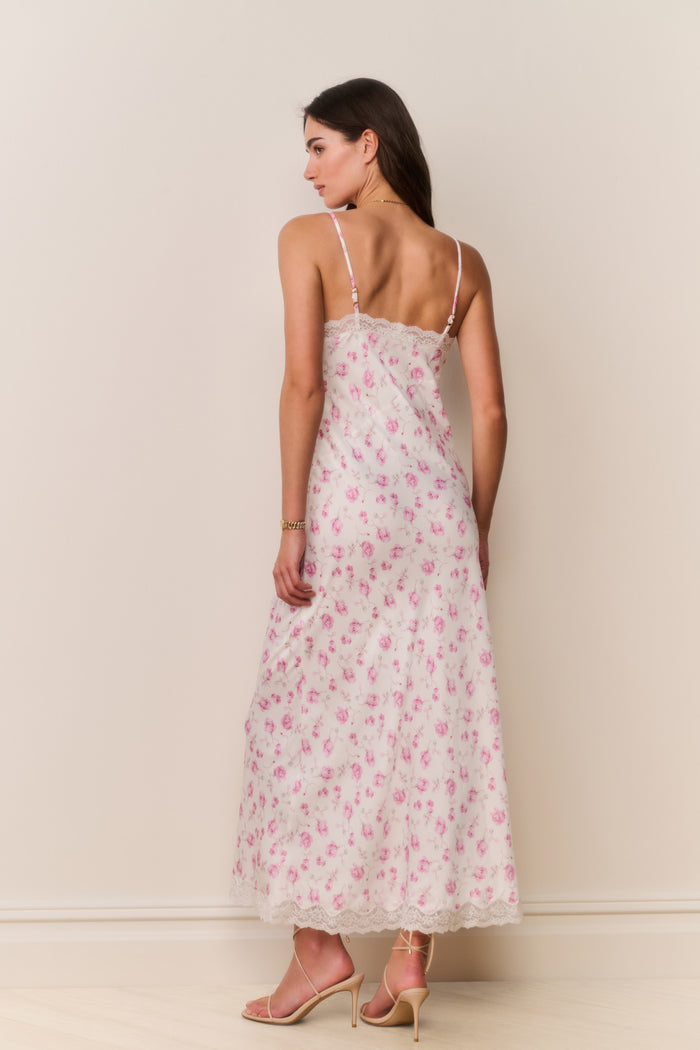 Woman wearing a white dress with pink floral pattern on a white background