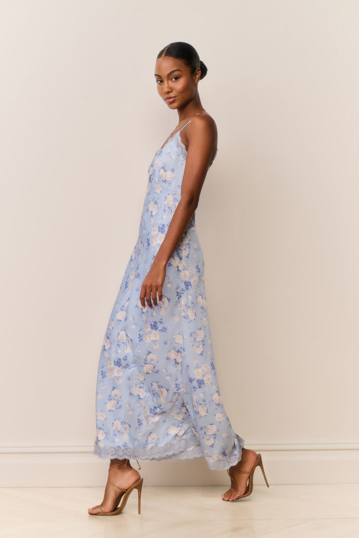 Woman wearing a light blue floral dress against a plain background