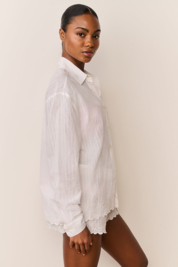 Woman wearing a white lace-trimmed shirt against a plain background