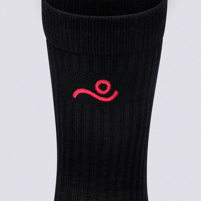 A close-up of a black ribbed athletic sock featuring a small red embroidered logo on the side, set against a plain light gray background.