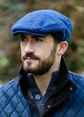 Man wearing a mucros trinity blue cap and quilted jacket outdoors