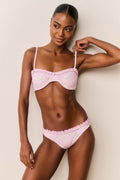 Woman wearing a pink floral bikini with a white background