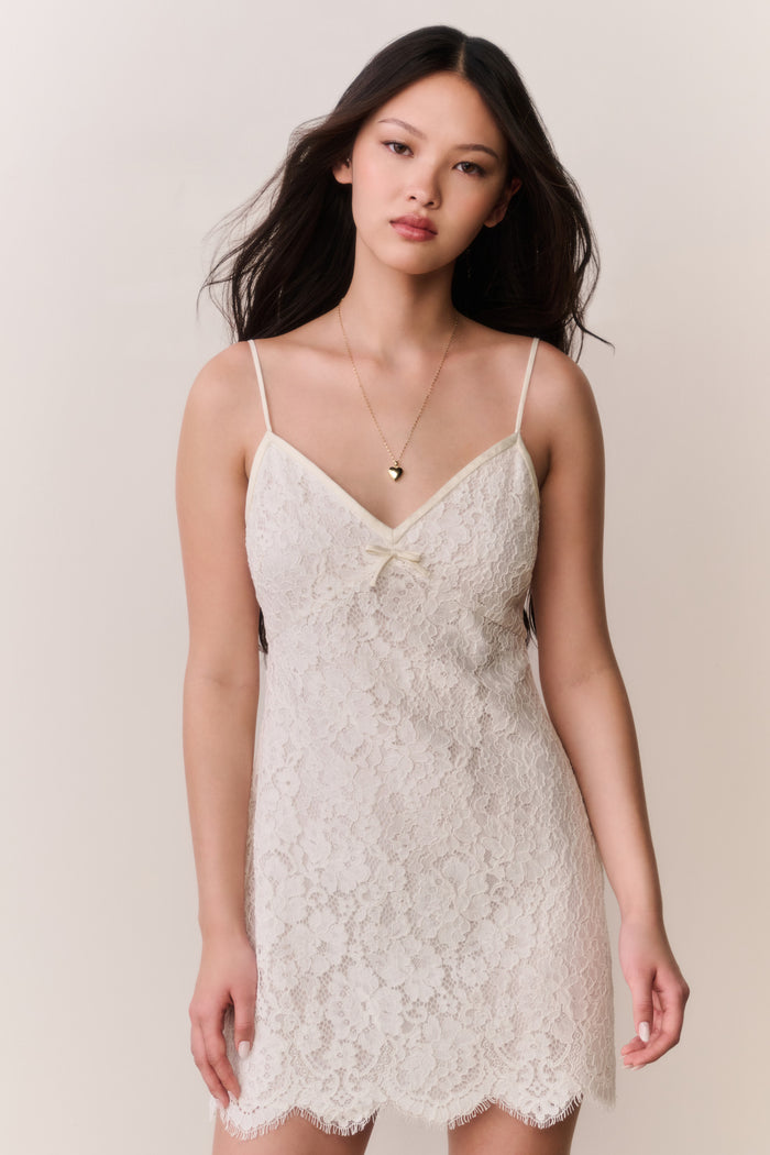 Woman wearing a white lace dress against a plain background