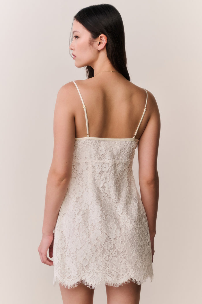 Woman wearing a white lace dress against a plain background