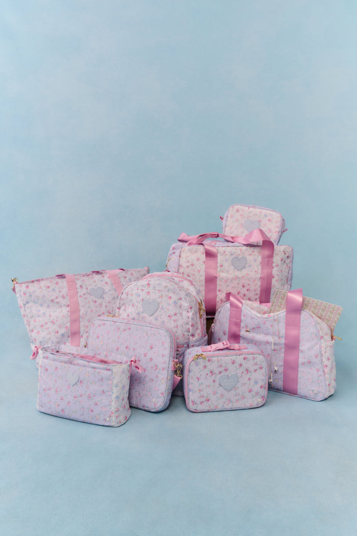 Floral print pink luggage collection against blue background