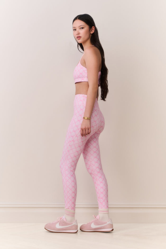 Woman wearing a pink athletic outfit on a plain background