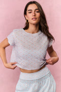 Woman wearing a light blue top and pants with a subtle pattern against a pink background