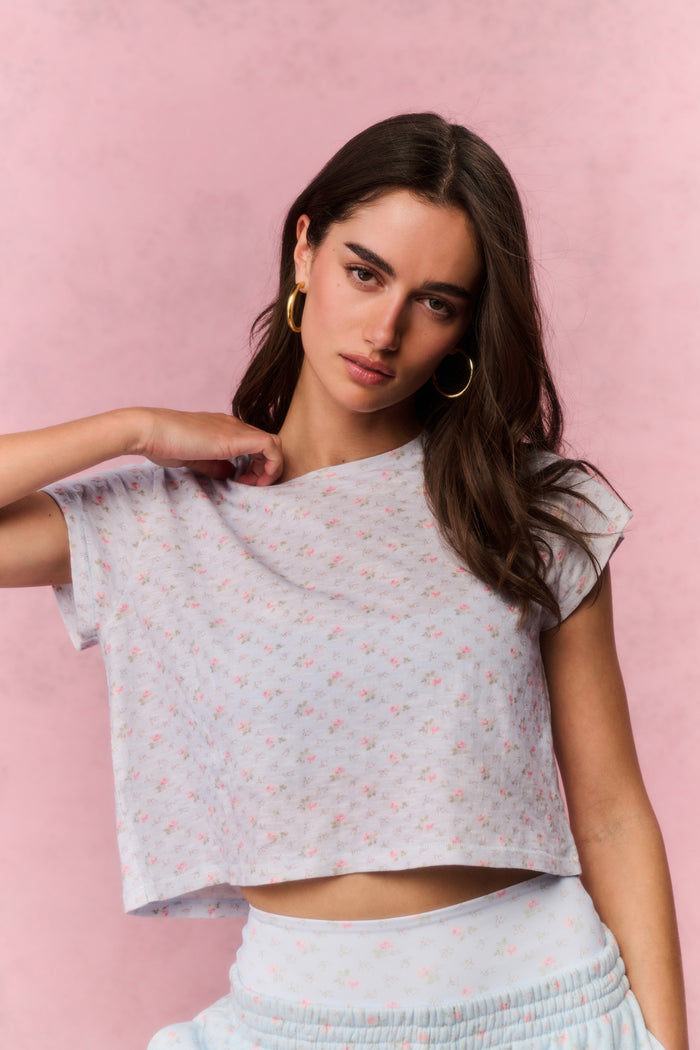 Woman wearing a light blue top and pants with a subtle pattern against a pink background