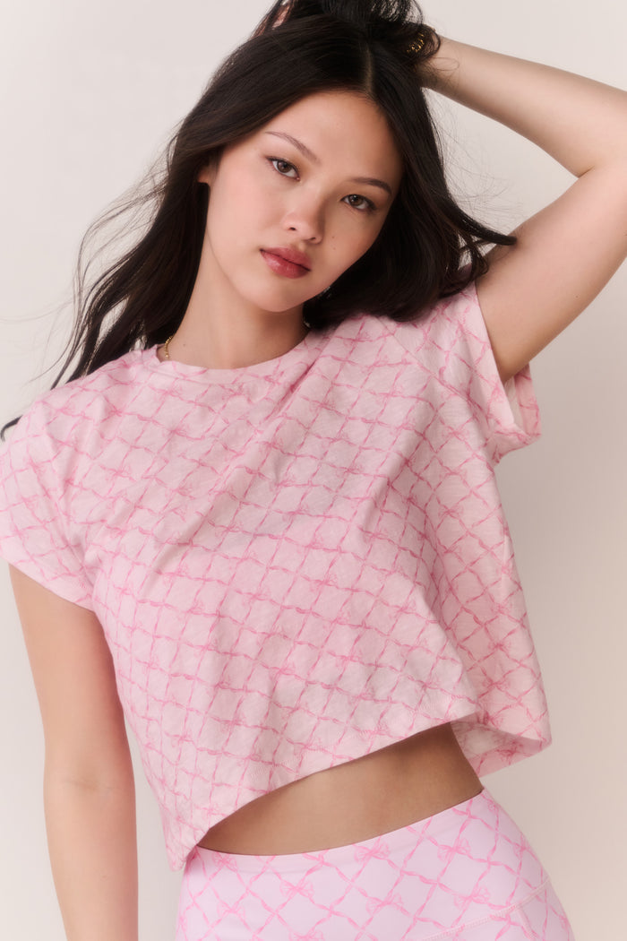 Woman wearing a pink bow patterned t-shirt and matching leggings outfit against a plain background