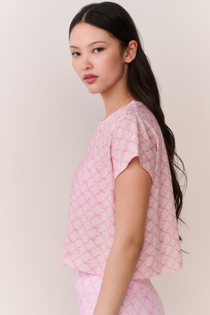 Woman wearing a pink bow patterned t-shirt and matching leggings outfit against a plain background